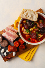 Traditional Spanish goulash soup. Fabada Asturiana. Served with a yellow clay pot with lid. Top...