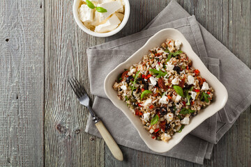 Trendy lunch with red rice, a mix of groats and vegetables. Top view. Served in white bowl on grey wooden background.