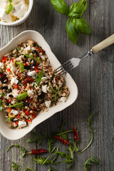 Trendy lunch with red rice, a mix of groats and vegetables. Top view. Served in white bowl on grey wooden background.