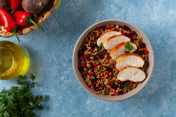 Trendy lunch with cereal, beetroot and chicken. Served in a bowl on a blue painted background. Top view.