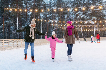 christmas, family and leisure concept - happy mother, father and daughter at outdoor skating rink in winter