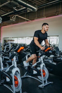 Sporty Man Riding Spinning Bikes At Gym.