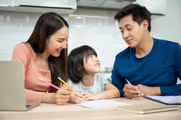 Obraz premium Asian father, mother and daughter doing home work togather in living room, education at home and family concept