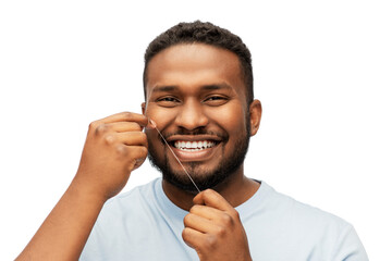 health care, hygiene and people concept - smiling african american young man with dental floss cleaning teeth over white background