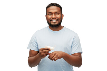 grooming, skin care and people concept - happy african american man applying moisturizer to his hand over white background