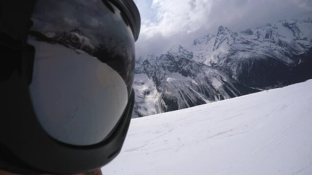 Unusual view from action camera aimed at mask of snowboarder gets up from slope