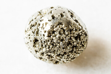 closeup of sample of natural mineral from geological collection - polished Pyrite (iron pyrite, fool's gold) rock on white marble background from Ancash, Bolognesi, Huallanca, Huanzala Mine in Peru