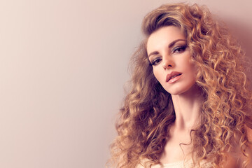 Fototapeta premium Beauty fashion woman portrait. Gorgeous young blonde with long curly hair healthy skin, makeup. Female face close up. Beautiful smiling model girl, fashionable hairstyle. Skincare make up concept