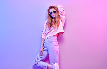 Fashionable hipster woman in Trendy outfit, stylish hair, makeup on pink purple neon light. Redhead...