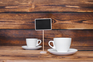 White coffee cups with a sign on a dark wood texture background