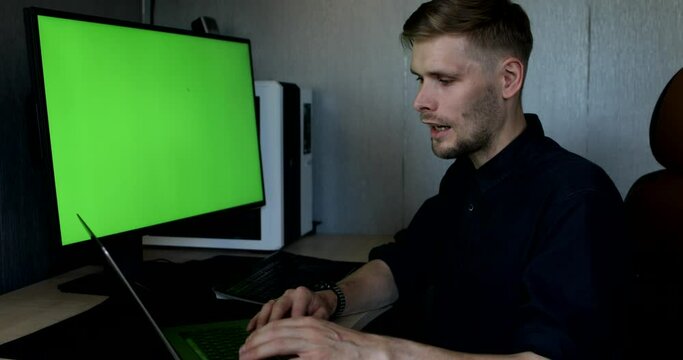 Man sitting by powerful personal computer with mock-up green screen monitor. Virtual business team meeting online at home. Teleworking over a video call on computer. Work from home 