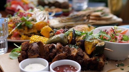 Close up of soy meat and vegetable barbecue served with sauces and a side salad