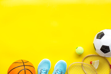 Sport games equipment - balls, sneakers, rackets - on yellow top view copy space