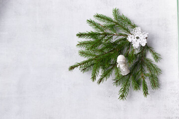 Fir tree branches and white crocheted angel and snowflake on light background with copy space. Christmas hamdmade gift concept.