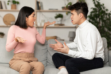 Chinese Couple Having Quarrel Arguing Sitting On Couch At Home