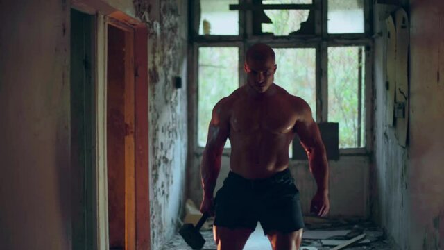 An athletic man with a naked torso walks through a destroyed building medium shot