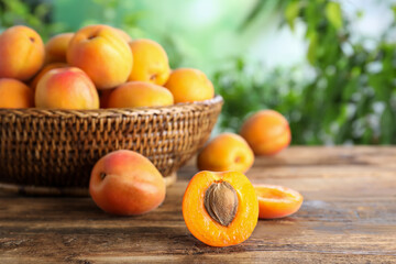 Fototapeta na wymiar Many fresh ripe apricots on wooden table against blurred background