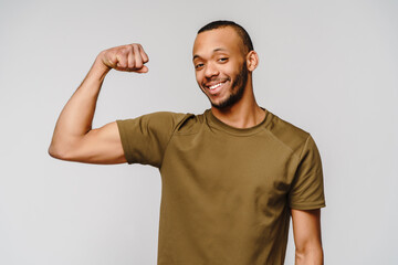 Close up portrait of a happy african american man wearing t-shirt flexing bicep arm muscle