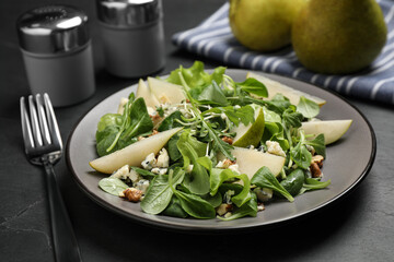 Tasty salad with pear slices and fork on black table, closeup