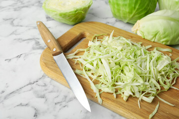 Chopped ripe cabbage and knife on white marble table, closeup