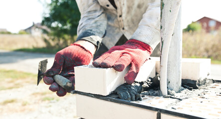 A worker builds a fence post from bricks