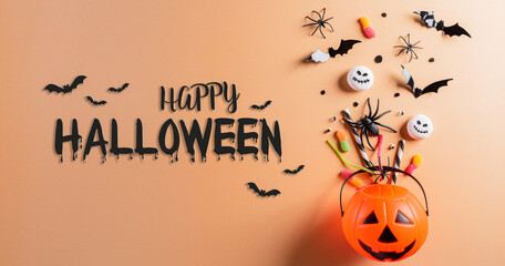 Top view of Halloween crafts, orange pumpkin, ghost, bat and black spider on pastel orange background. Flat lay, top view with Happy Halloween text.