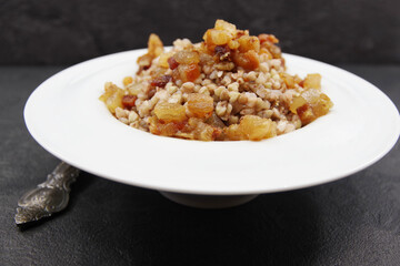 Buckwheat porridge with pork cracklings served in a plate. Black background. Closeup