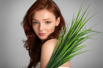 Naklejka premium Red-Haired Young Lady Posing With Green Leaves Over Gray Background