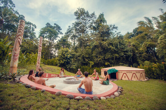 Group of people preparing for Mayan Temazcal- traditional steam sauna bath of Mesoamerican cultures. Diverse multiethnic friends sitting on grass and taking training course before Temazcal experience