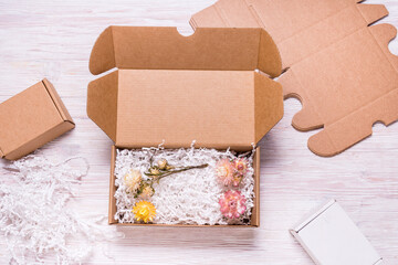 Brown cardboard box with paper filler on wooded desk, top view