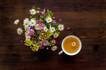Wild flowers with herbal tea on a table top view, copy space