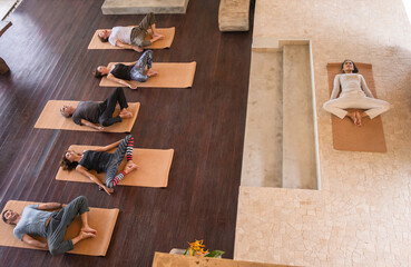 Diverse group of people on wooden floor practicing yoga lying in Reclined Butterfly exercise relaxing after practice. Healthy lifestyle