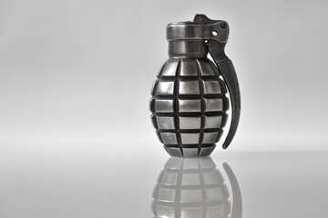 A lighter like hand grenade  on grey background with a reflection.