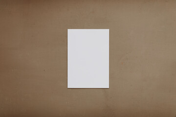 Blank white page on brown background. Modern stationery still life. Closeup of blank greeting card mock up scene. Brown table background. Flat lay, top view.