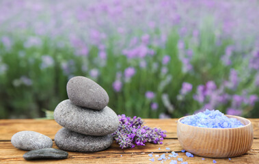 Fototapeta na wymiar Spa stones, fresh lavender flowers and bath salt on wooden table outdoors, closeup