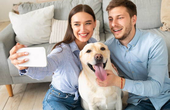 Young couple taking selfie with their dog at home