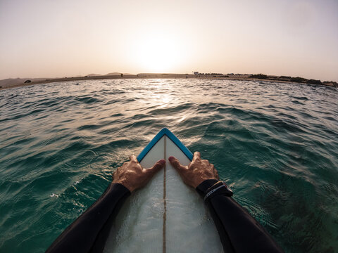 Surfer pov watching sunset in the water sitting on his surf board - Freedom, holidays, vacation concept