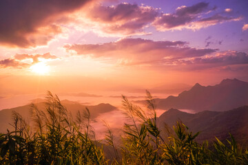 Beautiful landscape nature of sunrise on peak mountain with sun cloud fog and bright colors of sky in winter at Phu Chi Fa Forest Park is a famous tourist attraction of Chiang Rai Province, Thailand