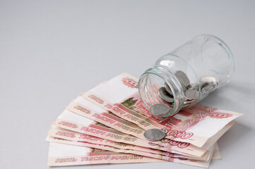 A glass jar with coins is on five-thousand-dollar bills, the concept of interest on deposits in banks