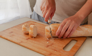 Cutting fresh crispy bread close-up. The woman is cutting bread.
