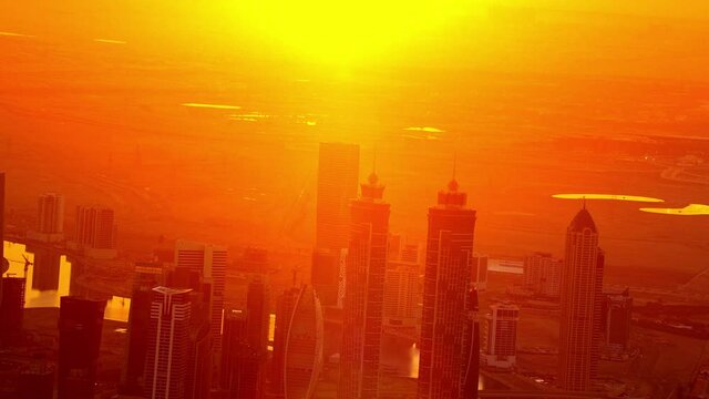 A captivating color of the horizon with the extreme aerial view of the  JW Marriott Marquis Hotel in downtown Duabi capturing and amazing orange and yellow hue of the horizon ,6-axis, F1, 8K, parallax