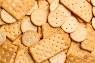 Many delicious crackers as background, top view