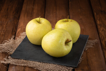Eco fruits - fresh yellow apples on wooden background, vegan food