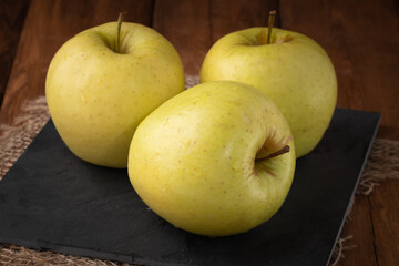 Eco fruits - fresh yellow apples on wooden background, vegan food