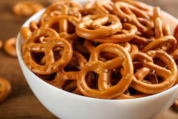 Delicious pretzel crackers in bowl on wooden table, closeup