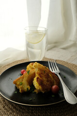 Roasted cauliflower with tomato cherries and fresh parsley on the black plate with a glass of water