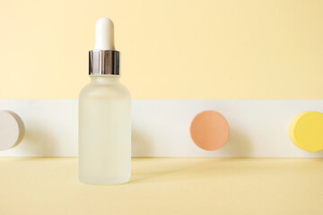 Anti-aging hyaluronic acid facial serum on pastel yellow background with neo-geometric conceptualism decor, front view. Mockup skincare cosmetic product