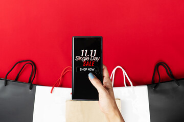 woman hand holding smartphone with shopping bag, China 11.11 single day sale concept