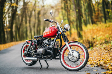 Red custom old fashioned motorcycle on the road in the forest