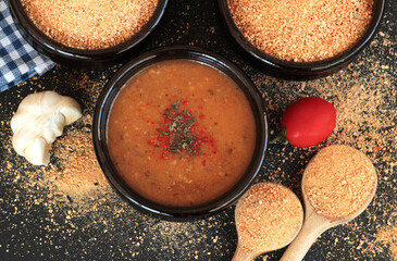 Traditional Turkish Homemade Dry Soup,Tarhana grains and cooked in casserole bowl on black surface with ingredients